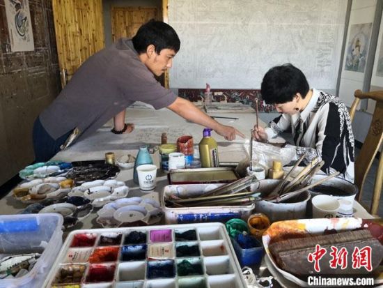 圖為2020年8月下旬，敦煌“80后”畫家張杰龍(左)在為云南麗江“學生”莫北講解敦煌壁畫的繪畫技巧?！●T志軍 攝