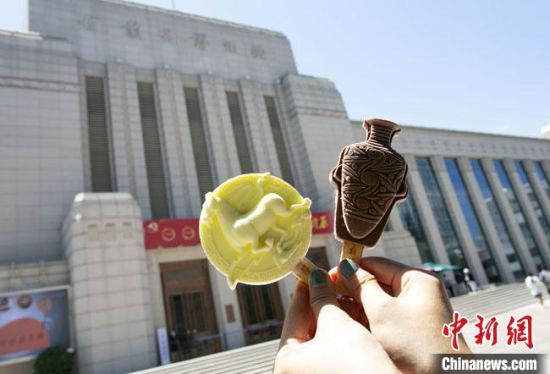 2021年7月30日，游客手拿“銅奔馬”“彩陶瓶”造型的雪糕，在甘肅省博物館前拍照打卡?！「哒?攝