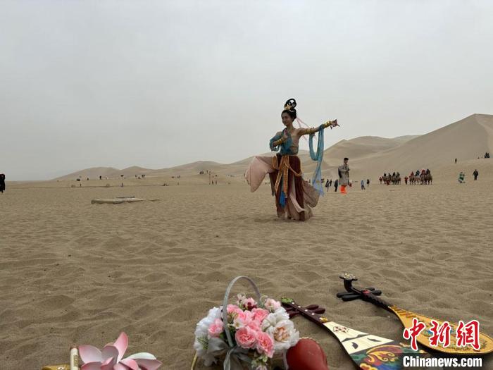 圖為2023年4月底，敦煌大漠“逐舞者”奧楠在鳴沙山月牙泉景區(qū)視頻直播敦煌舞?！●T志軍 攝