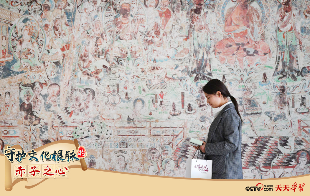 2023年4月25日，敦煌研究院文物數(shù)字化保護(hù)團(tuán)隊(duì)創(chuàng)意營銷人員廖雪婷從一幅高保真復(fù)制壁畫前走過。
